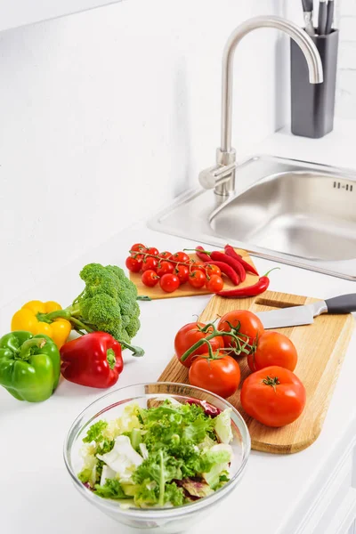 Delicious tomatoes and chili peppers on cutting boards in light kitchen — Stock Photo