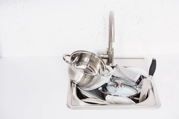 Pilha de panela suja, pratos, ralador e tampa da panela na pia na cozinha — Fotografia de Stock