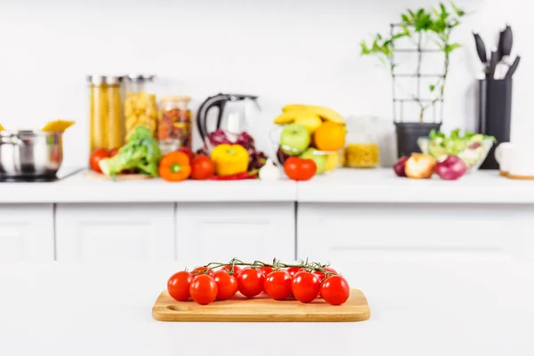 Ripe cherry tomatoes on cutting board in light kitchen — Stock Photo