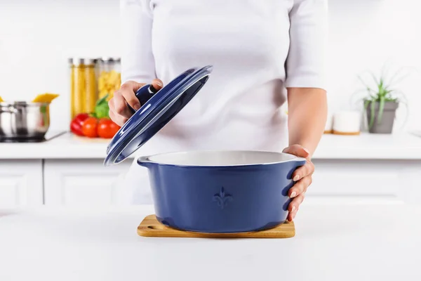 Imagen recortada de la mujer sosteniendo la sartén y la tapa en la cocina ligera - foto de stock