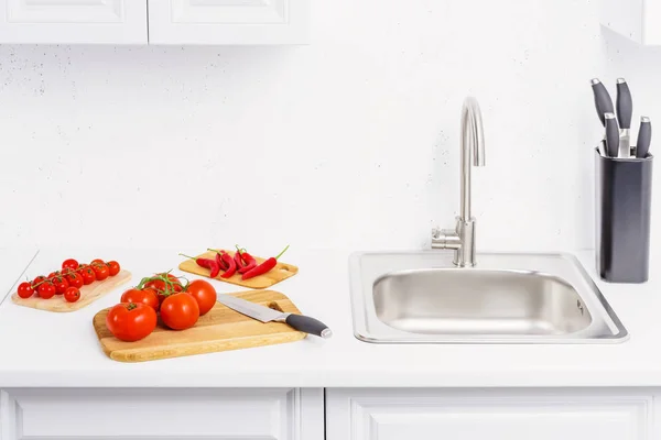 Tomates maduros, tomate cereja e pimentão em tábuas de corte na cozinha leve — Fotografia de Stock