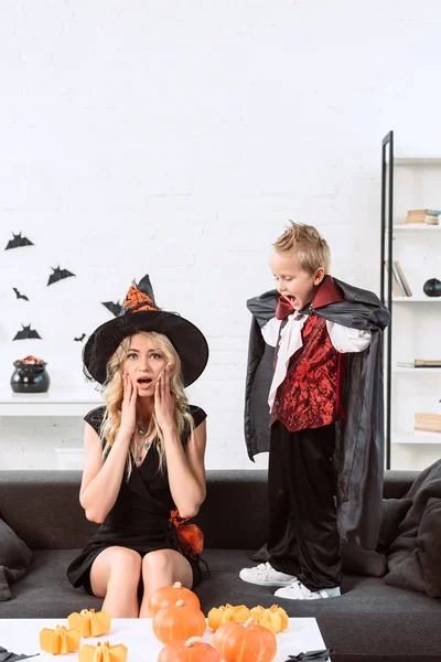 Little boy in vampire costume screaming at mother in witch halloween costume at home — Stock Photo