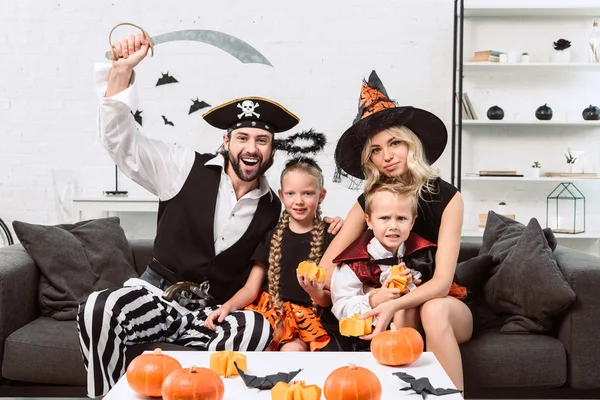 Porträt einer Familie in verschiedenen Halloween-Kostümen am Kaffeetisch mit Kürbissen zu Hause — Stockfoto