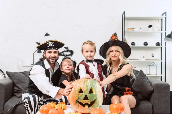 Porträt einer Familie in verschiedenen Halloween-Kostümen am Kaffeetisch mit Kürbissen zu Hause — Stockfoto