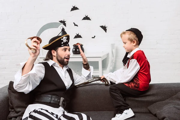 Padre e hijo en trajes piratas jugando en casa, concepto de fiesta de Halloween - foto de stock