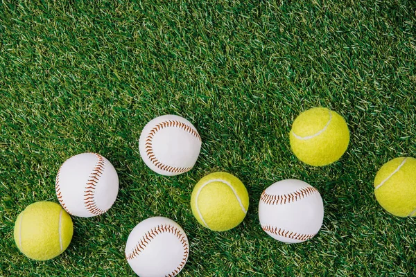 Posa piatta con disposizione di palline da tennis e baseball su erba verde — Foto stock