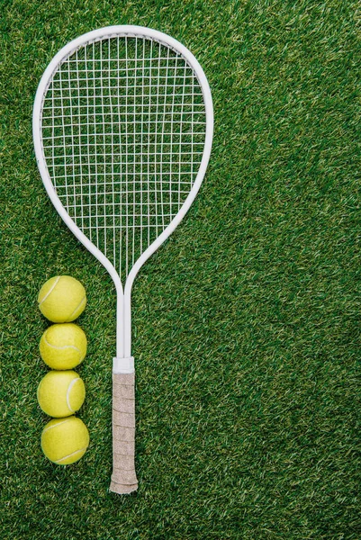 Blick von oben auf Tennisschläger und Bälle aus grünem Gras — Stockfoto