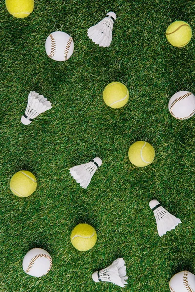 Top view of arrangement of badminton shuttlecocks, tennis and baseball balls on green lawn — Stock Photo