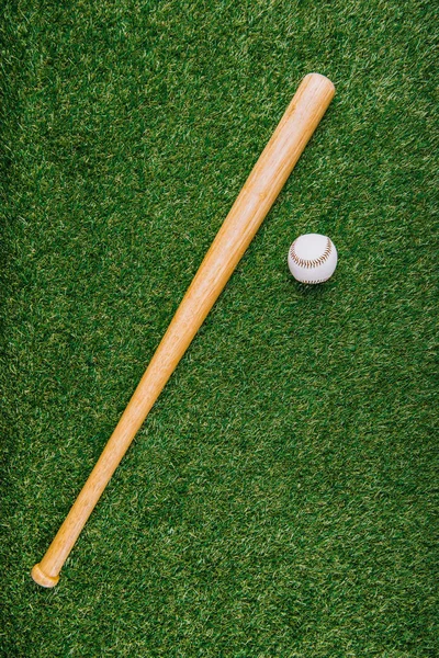 Vue de dessus de la batte de baseball et balle disposée sur la pelouse verte — Photo de stock
