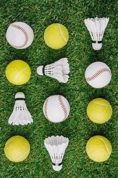 Top view of arrangement of badminton shuttlecocks, tennis and baseball balls on green lawn — Stock Photo