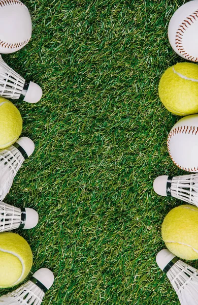 Top view of arrangement of badminton shuttlecocks, tennis and baseball balls on green lawn — Stock Photo