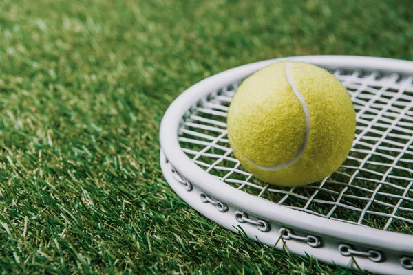 Close up view of tennis ball on racket lying on green lawn — Stock Photo