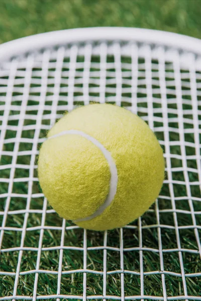 Vue rapprochée de balle de tennis sur raquette couchée sur pelouse verte — Photo de stock