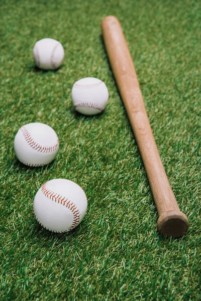 Close up view of baseball bat and balls arranged on green lawn — Stock Photo