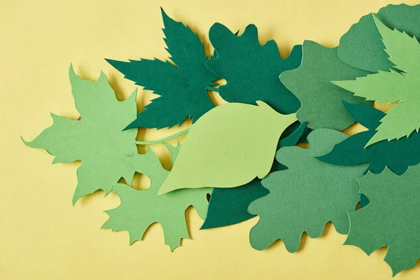 Quadro completo de folhagem de papel artesanal verde dispostos em fundo amarelo — Fotografia de Stock