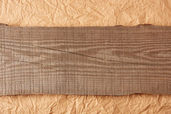 Top view of wooden plank on crumpled paper backdrop — Stock Photo