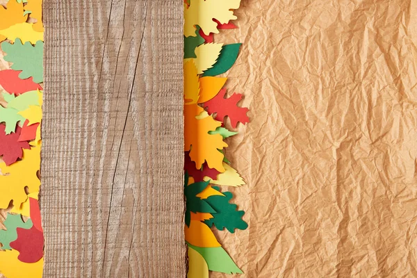 Top view of wooden plank and colorful paper leaves arrangement on crumpled paper backdrop — Stock Photo