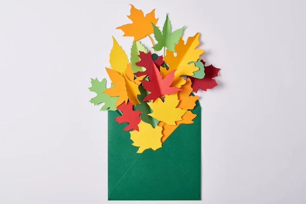 Vue du dessus de feuilles de papier colorées artisanales dans une enveloppe verte sur fond blanc — Photo de stock