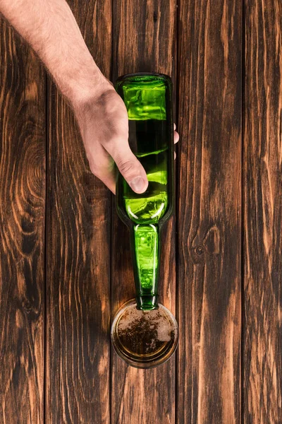 Partial view of man pouring beer into glass at wooden table — Stock Photo