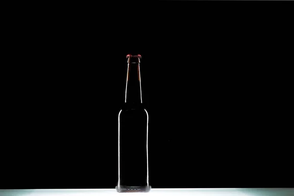 Garrafa de cerveja à mesa no fundo preto, conceito minimalista — Fotografia de Stock