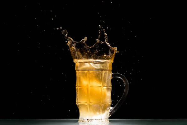 Verre de bière légère avec éclaboussures à table sur fond noir, concept minimaliste — Photo de stock