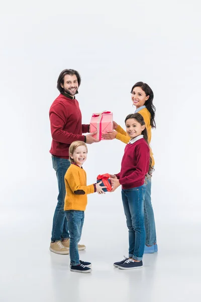 Padres felices y niños presentando regalos envueltos el uno al otro aislados en blanco - foto de stock