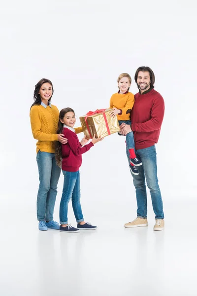 Smiling mother with daughter presenting wrapped gift to father with son and looking at camera isolated on white — Stock Photo