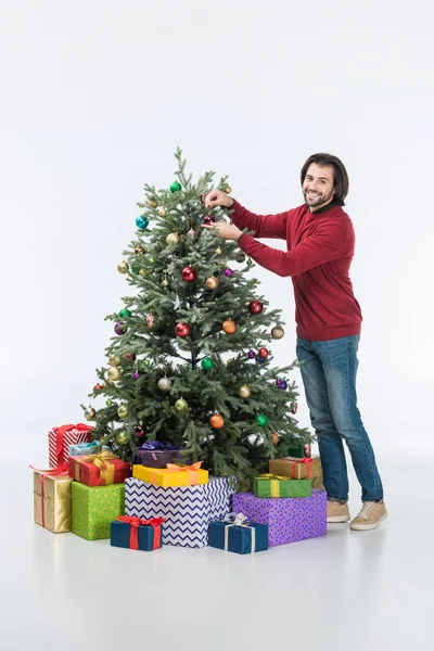 Homme heureux décorant arbre de Noël avec des boules de verre et regardant la caméra isolée sur blanc — Photo de stock