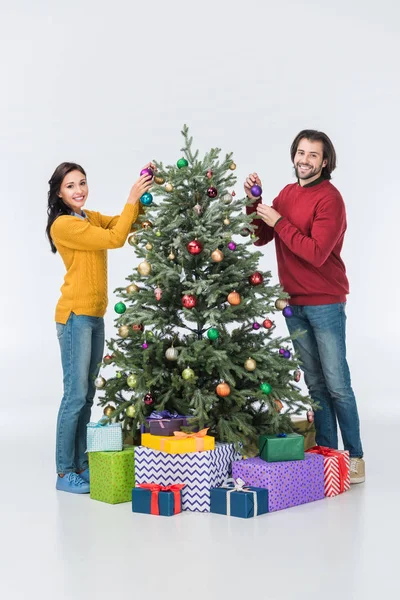 Feliz pareja decorando árbol de Navidad con bolas de vidrio aisladas en blanco - foto de stock