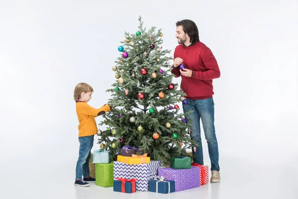 Padre con hijo decorando árbol de navidad con bolas de vidrio y regalos aislados en blanco - foto de stock