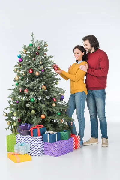 Felice marito abbracciando moglie decorare albero di Natale con regali isolati su bianco — Foto stock