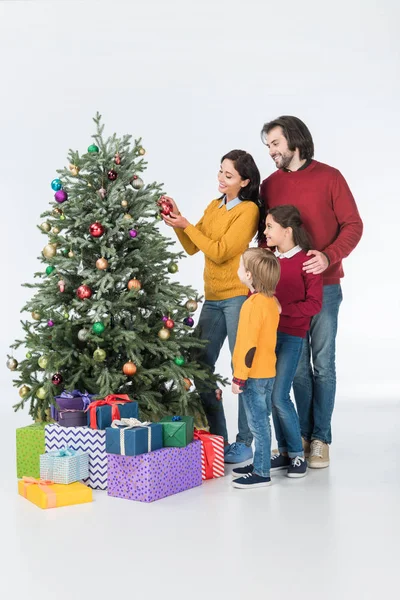 Familia de pie cerca de la madre decorando árbol de Navidad con regalos aislados en blanco - foto de stock