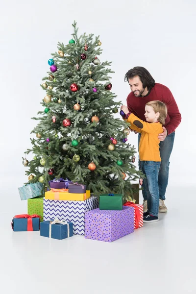 Улыбающийся отец с сыном украшает елку подарками, изолированными на белом — стоковое фото