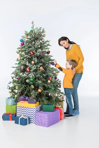Mère avec fils décorer arbre de Noël avec des cadeaux isolés sur blanc — Photo de stock