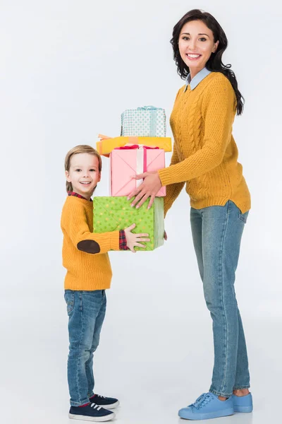 Sorrindo mãe e filho com presentes embrulhados olhando para a câmera isolada no branco — Fotografia de Stock