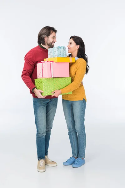 Lächelndes Paar mit verpackten Geschenken, das sich isoliert auf weiß anschaut — Stockfoto