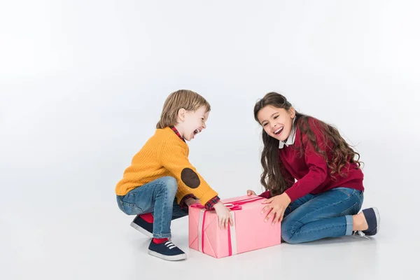 Hermanos felices con regalo rosa envuelto aislado en blanco - foto de stock