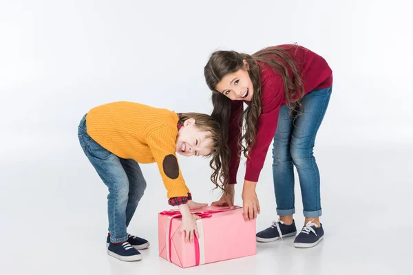 Smiling siblings with wrapped pink gift isolated on white — Stock Photo