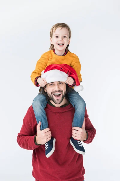 Lächelnder Vater mit Weihnachtsmütze, der Sohn auf den Schultern isoliert auf weißem Grund trägt — Stockfoto