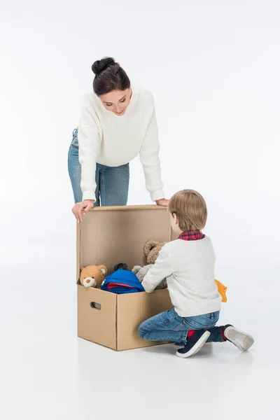 Mère avec fils regardant boîte en carton avec des jouets isolés sur blanc — Photo de stock