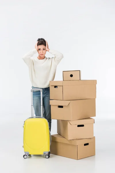 Femme stressée avec valise et boîtes en carton déménageant dans une nouvelle maison isolée sur blanc — Photo de stock