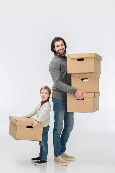 Father holding stack of cardboard boxes and son helping him isolated on white — Stock Photo