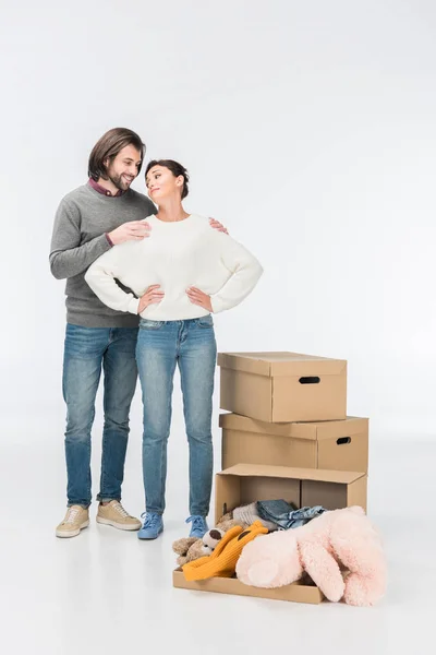 Paar steht neben Karton mit Spielzeug und sieht sich isoliert auf weißem Grund an — Stockfoto