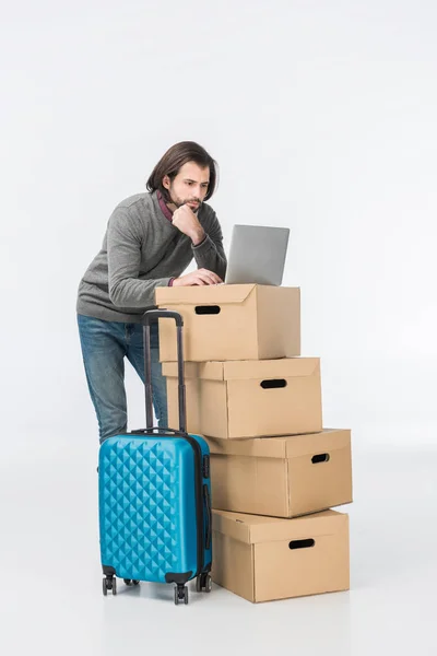 Hombre usando el ordenador portátil en cajas de cartón aisladas en blanco - foto de stock