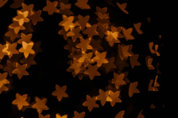 Vista de cerca de las estrellas doradas luces bokeh sobre fondo negro - foto de stock