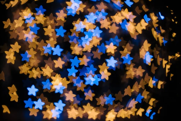 Marco completo de estrellas azules y doradas luces bokeh sobre fondo negro - foto de stock