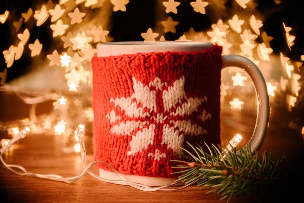 Vista de cerca de la taza de bebida caliente, guirnalda y rama de pino en la mesa de madera con estrellas bokeh luces de fondo - foto de stock