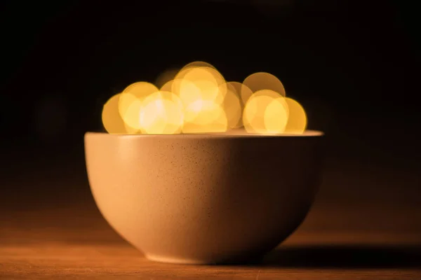 Close up view of bowl and bokeh lights on black background — Stock Photo