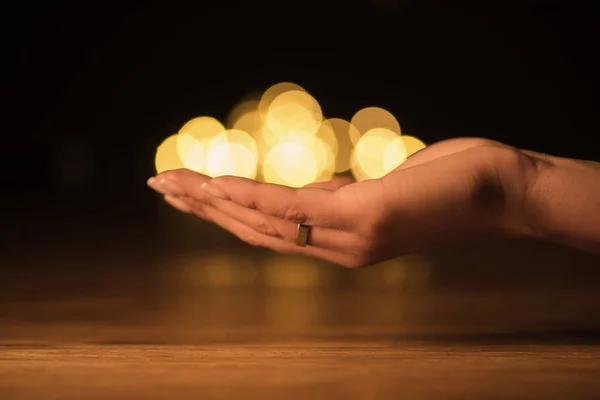 Partial view of woman holding bokeh lights in hand — Stock Photo