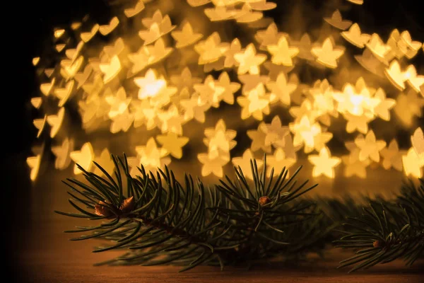 Close up view of pine tree branch and golden stars bokeh lights backdrop — Stock Photo